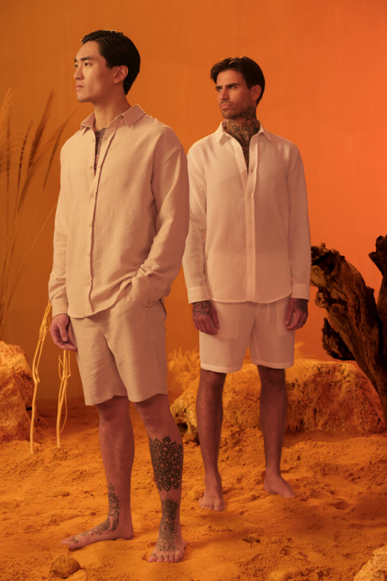 two male model posing on an orange set with our new collection
