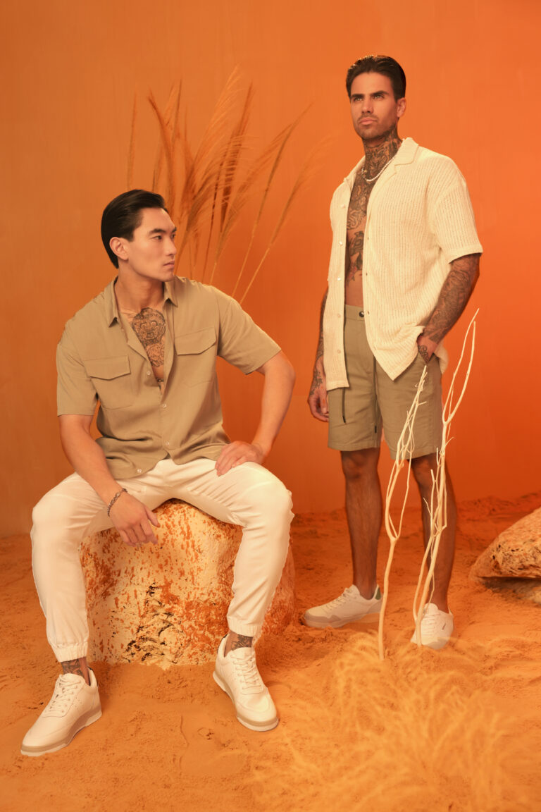 two male model posing on an orange set with our new collection