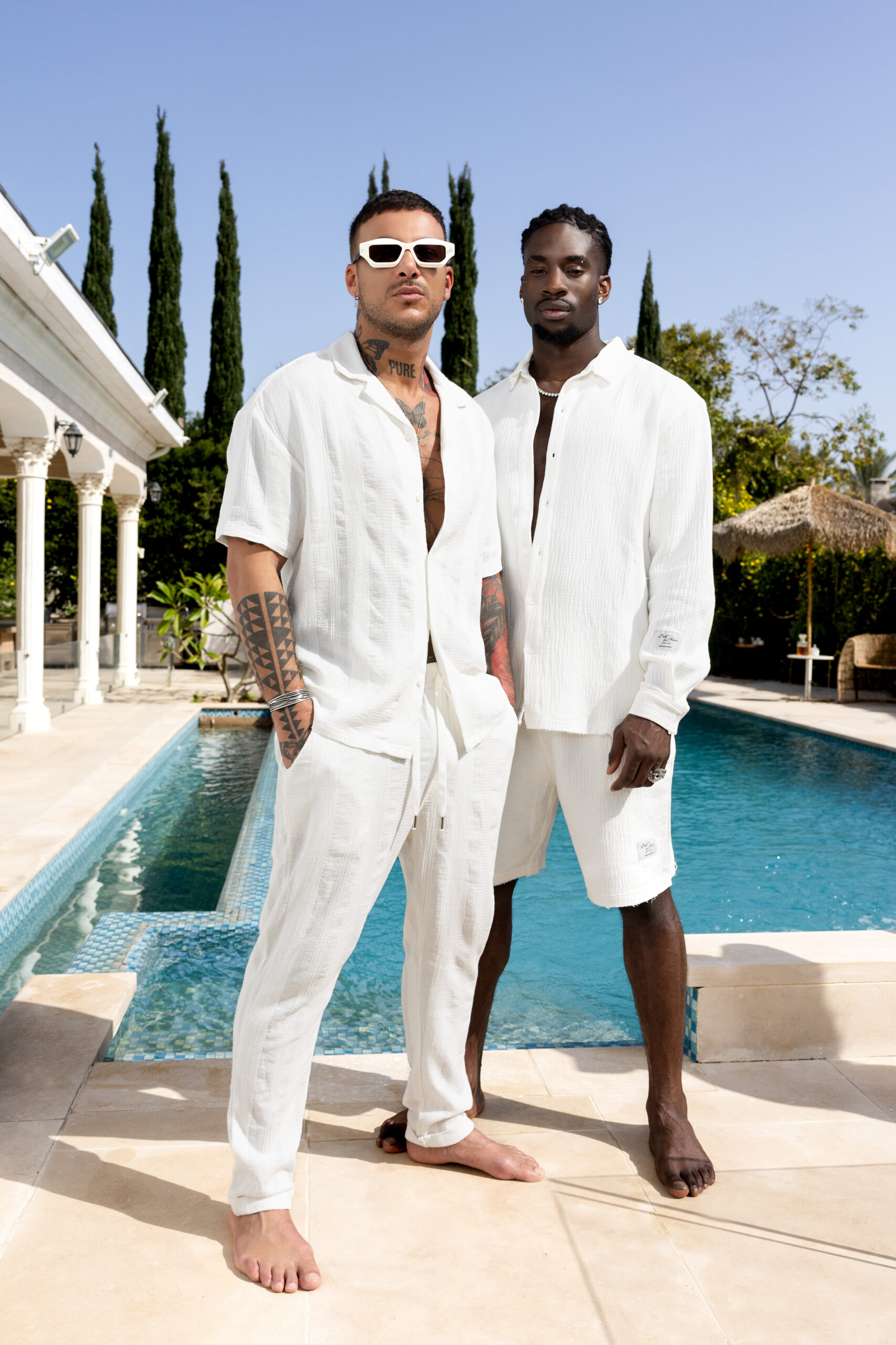 two male models with white clothing infront of a pool